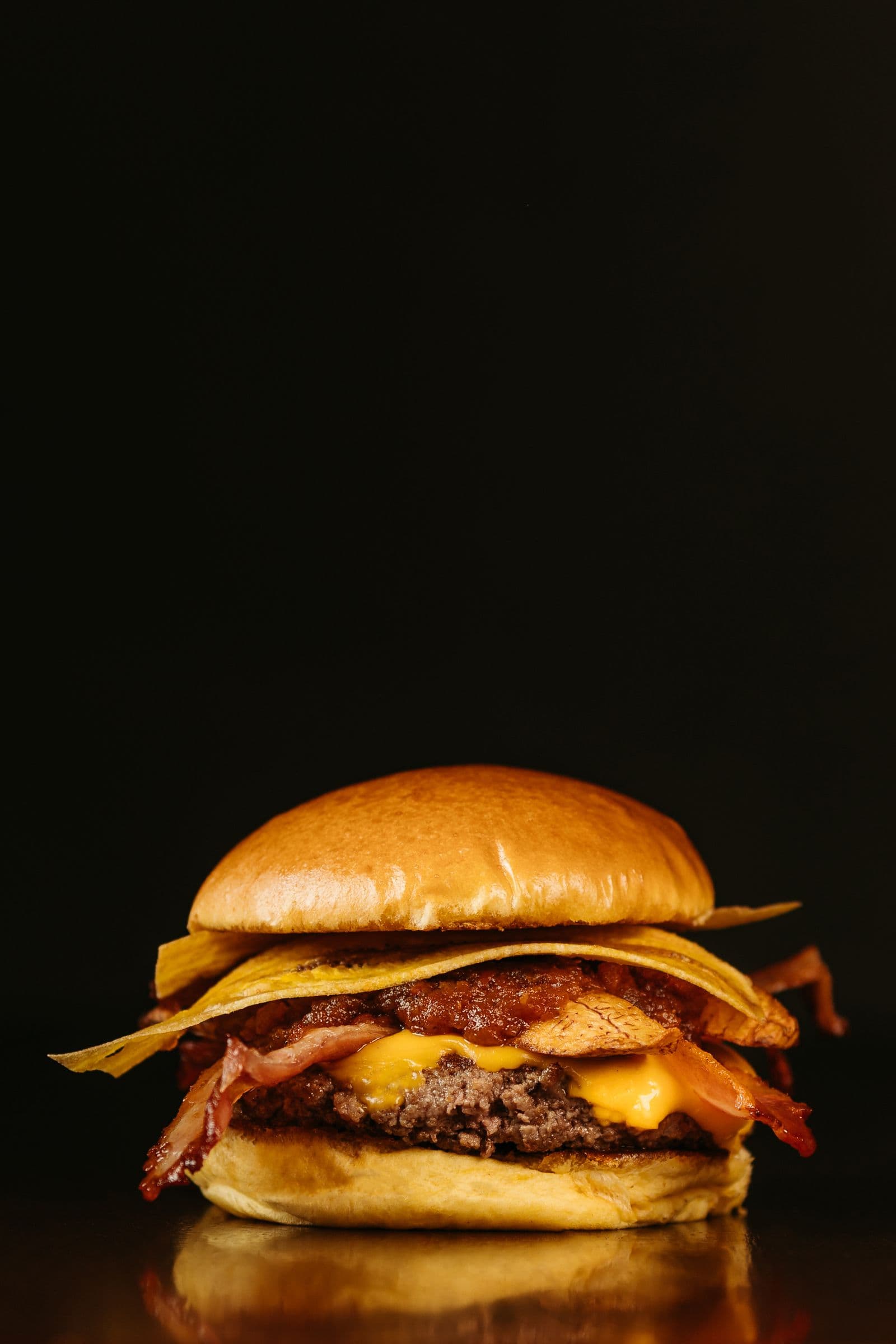 Hamburguesa gourmet iluminada sobre fondo negro